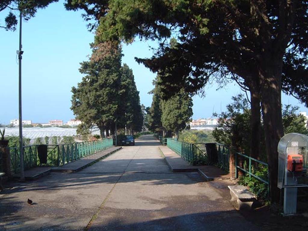 Herculaneum. May 2001. Looking south down roadway towards site. Photo courtesy of Current Archaeology.
The green railings on either side of the roadway provide a view from a bridge over the cryptoporticus of the Palaestra, on the left, and across the Herculaneum site below, on the right.
In 1954, in order to be able to excavate the cryptoporticus, Maiuri decided to construct a bridge, which at the time was considered a very modern and daring reinforced concrete bridge.
See Camardo, D, and Notomista, M, eds. (2017). Ercolano: 1927-1961. L’impresa archeologico di Amedeo Maiuri e l’esperimento della citta museo. Rome, L’Erma di Bretschneider, (p.345).